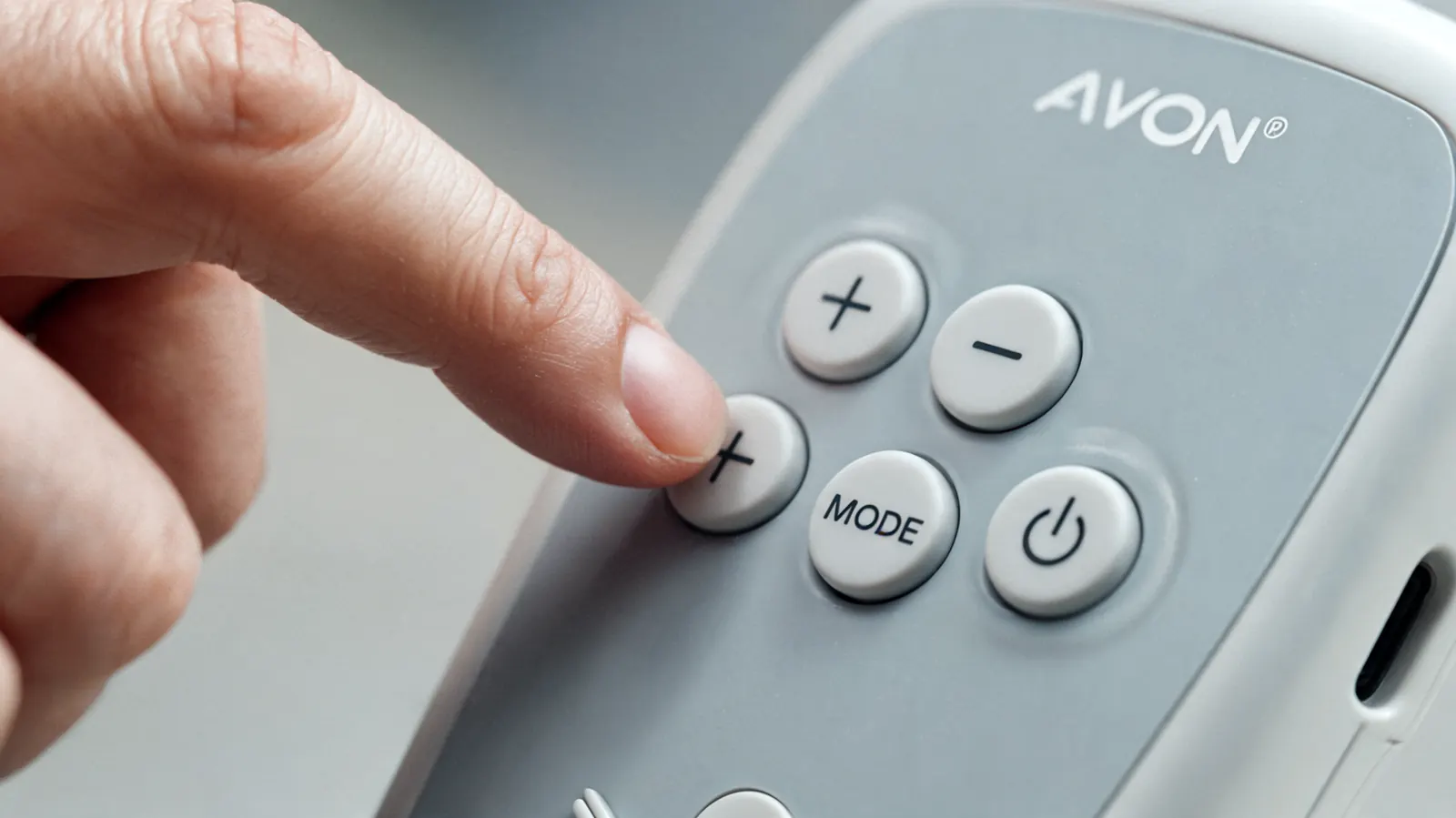Extreme close-up of the AUVON TENS unit control buttons showing how small and tightly spaced they are