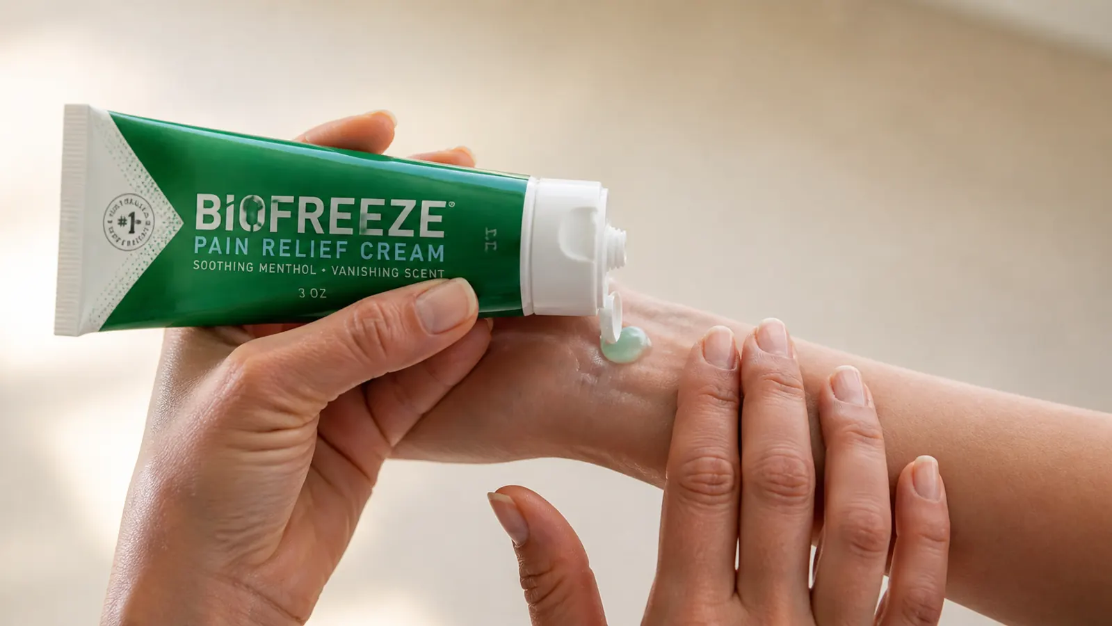 Hand applying Biofreeze green cooling cream to the inside of the opposite wrist, close-up, natural light