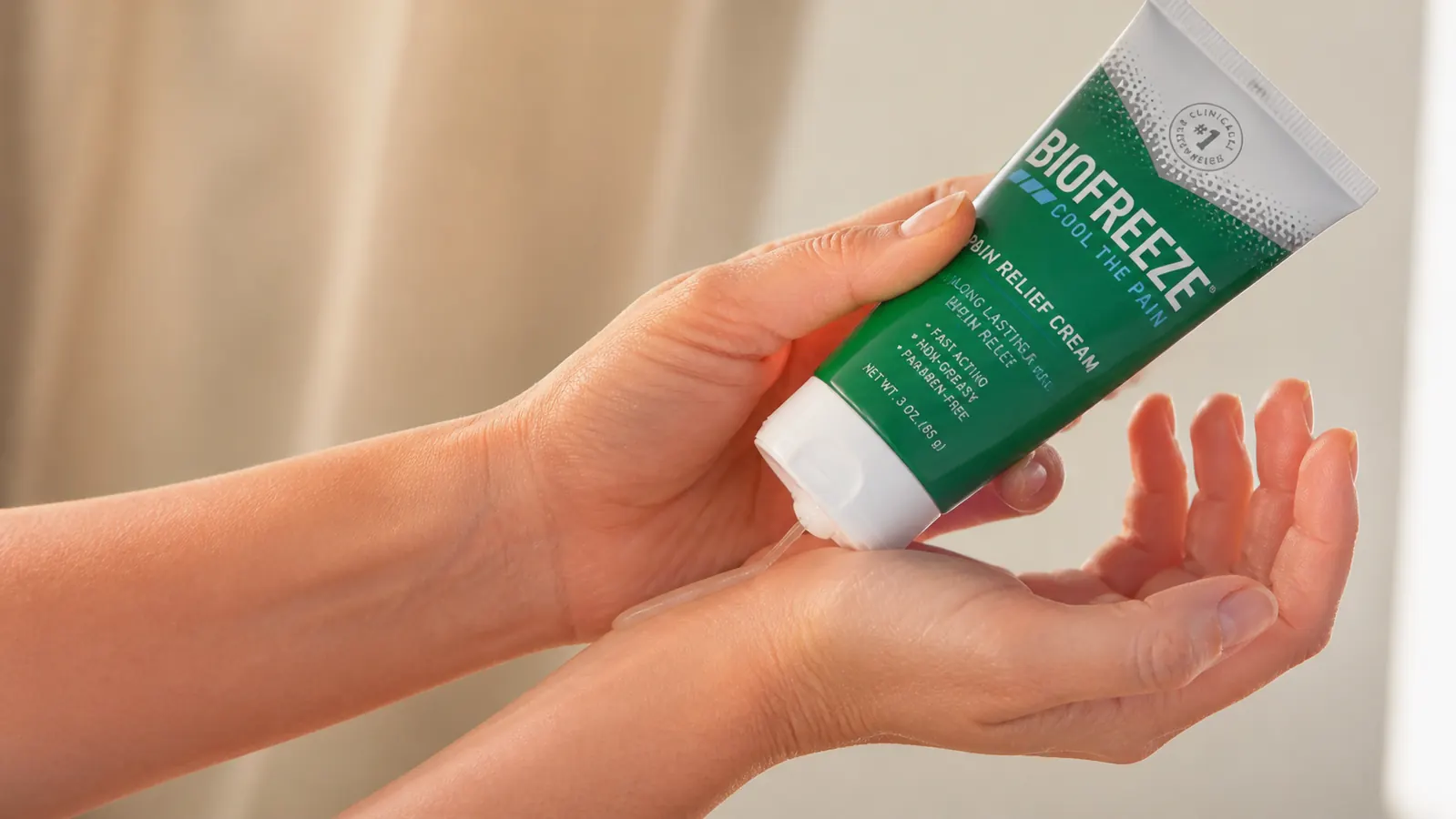 Hand squeezing a thin line of Biofreeze gel onto the wrist joint, close-up on the application